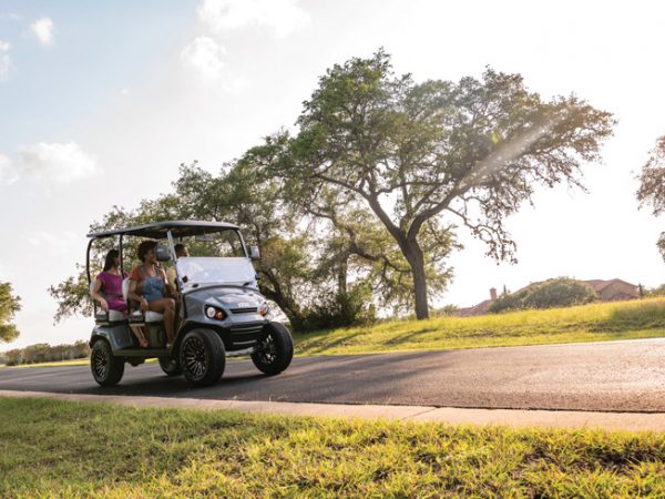 family riding in golf car on a sunny evening